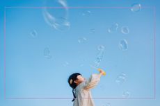 Inspirational quotes illustrated by girl with black hair blowing bubbles in big blue sky