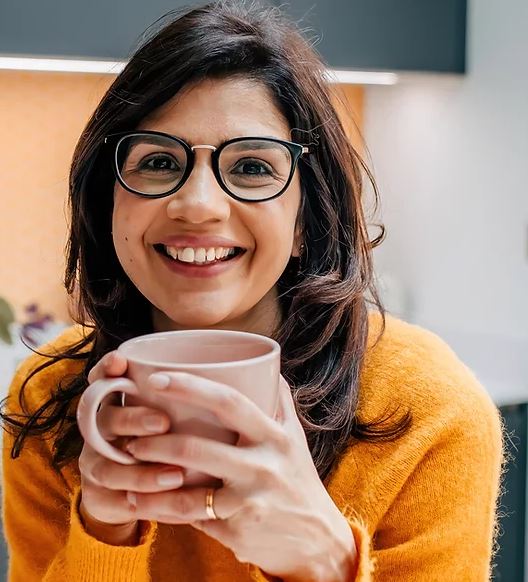 Image of woman holding a cup and smiling at camera