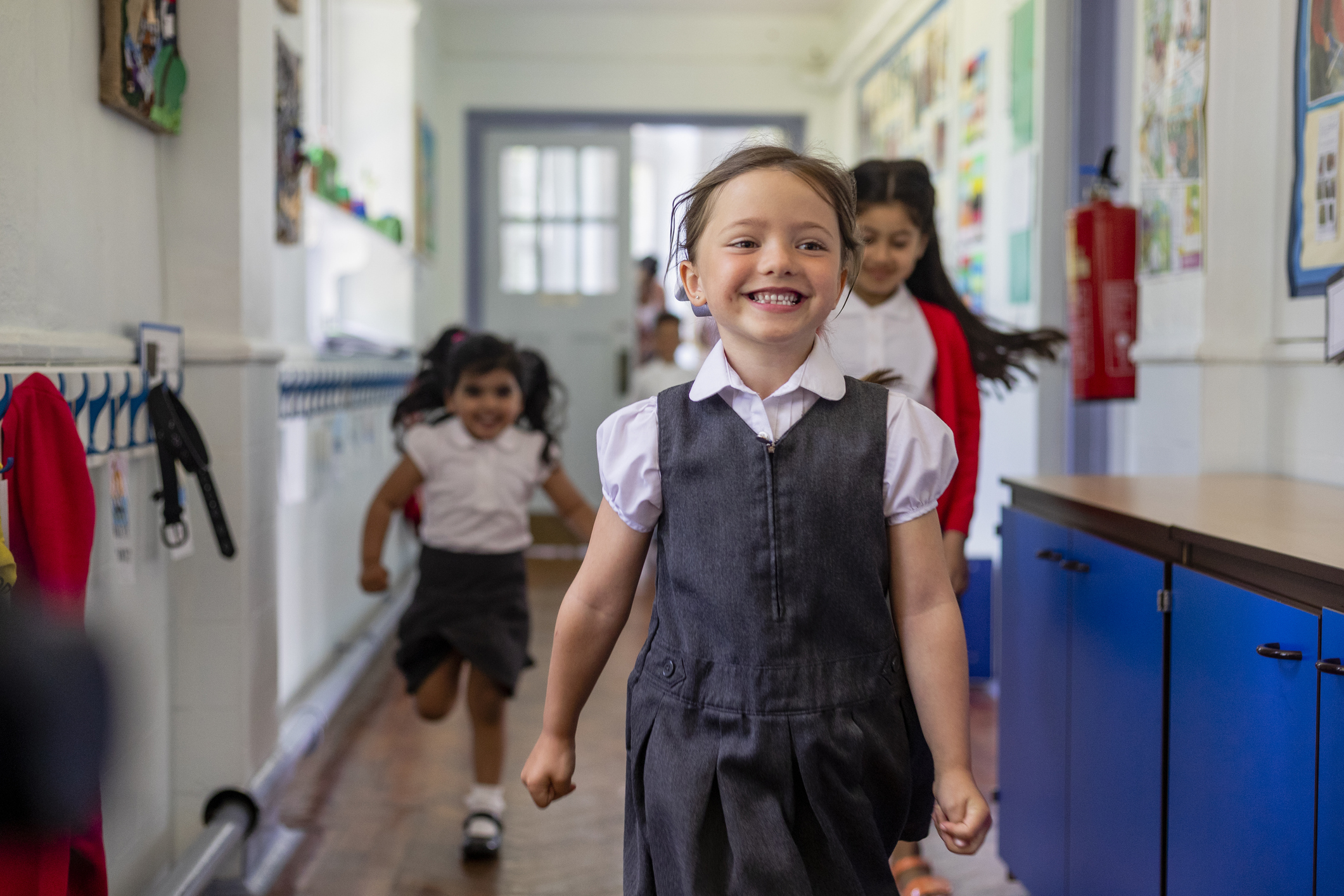 three school children in school corridor and wearing school uniform